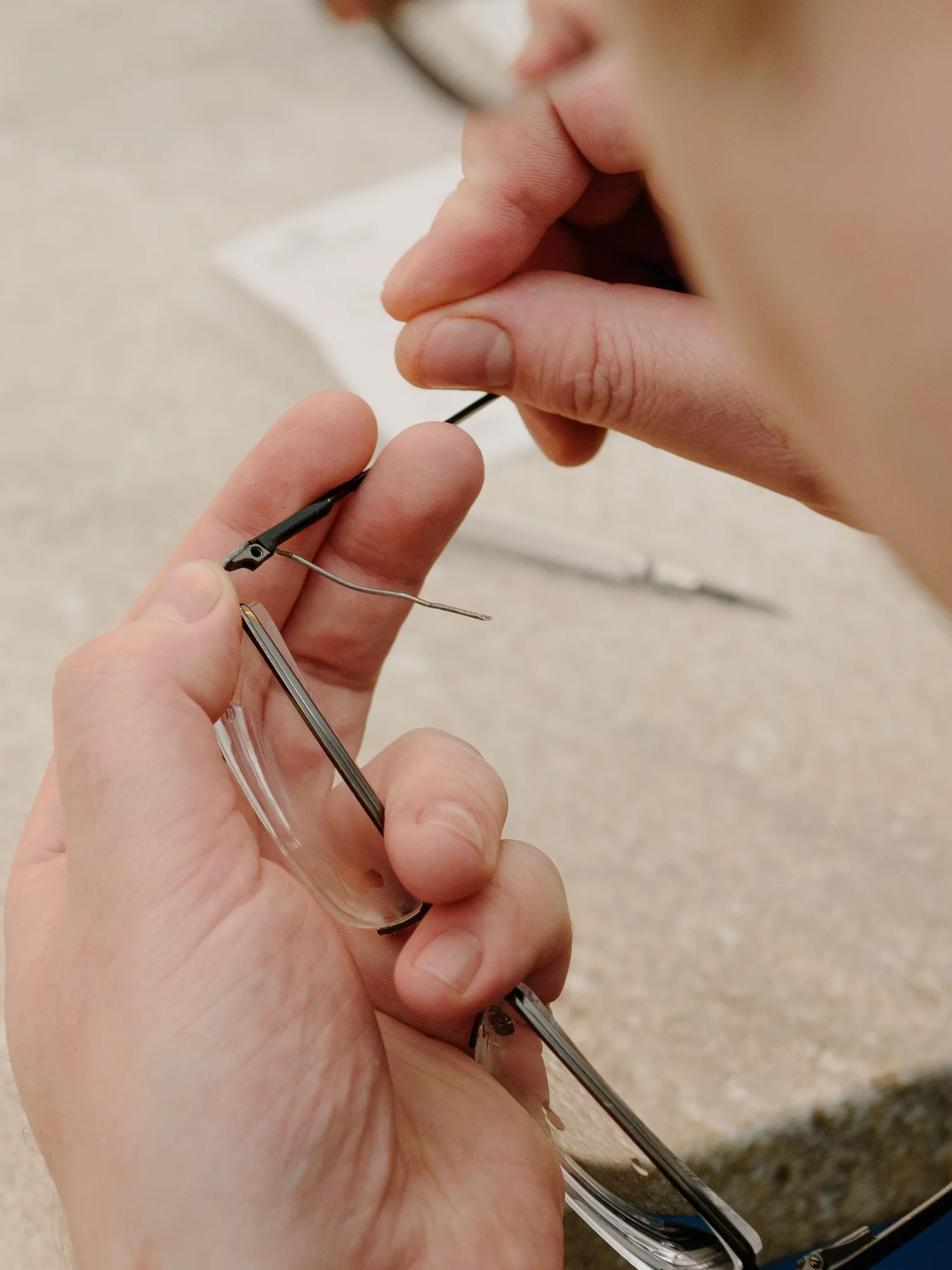 眼鏡のつるを工具で調整している手元